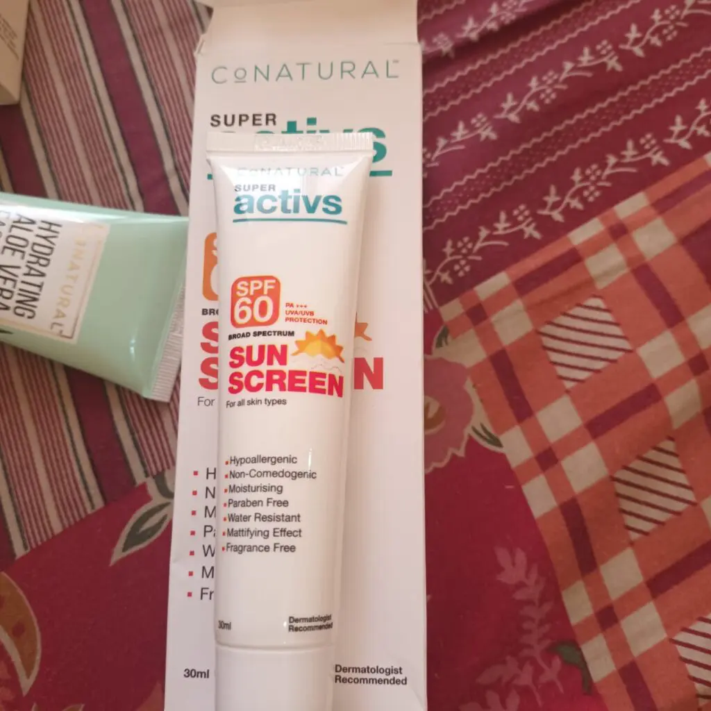 showing conatural sunscreen tube and packaging on a bed