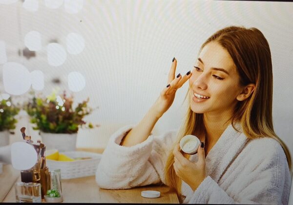 a woman applying moisturizer to her face